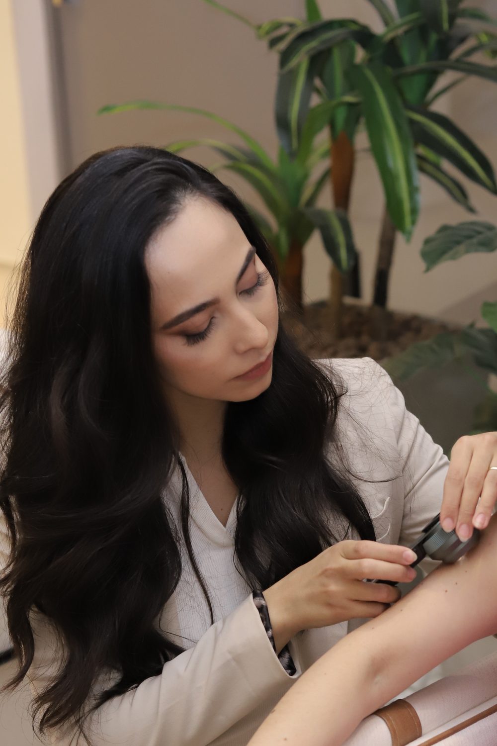 Dra. Stephanie Mansan examinando o braço de uma paciente com o dermatoscópio